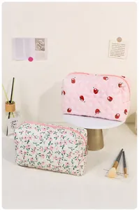 Detailed view of floral and strawberry quilted cosmetic bags with metal zippers