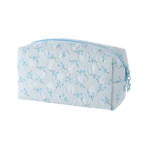 Floral blue cosmetic bag with star zipper pull and quilted texture for travel storage