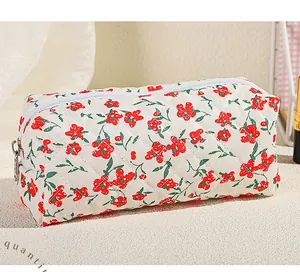 Detail of floral makeup bag featuring red flower print and quilted fabric texture