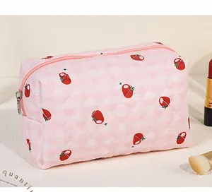 Detail of pink quilted cosmetics bag with red strawberry pattern and silver zipper