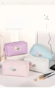 Four pastel bubble-textured makeup bags with bear patches on white display steps