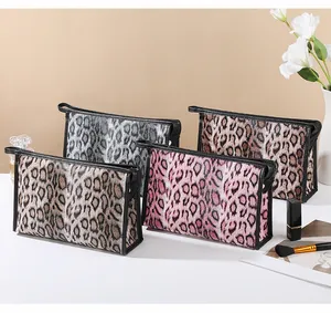 Detail view of four leopard print cosmetic bags in grey, brown, pink, and khaki colors