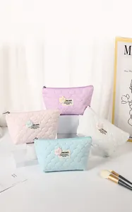 Detail of four macaron-colored bubble textured makeup bags with cute bear patches