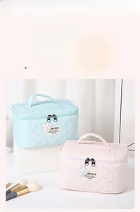 Detail of quilted texture makeup bags with bear pendants and top handles in pastel colors
