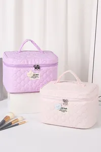 Detalle de neceseres acolchados en lavanda y rosa con textura ondulada y cierre de cremallera