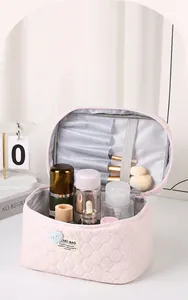 Interior del neceser rosa acolchado con compartimentos para brochas y cosmética