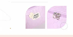 Detail of purple makeup bag with textured fabric, double metal zippers and cute bear label