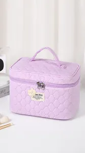 Detalle de neceser acolchado morado con diseño de ondas y cremalleras metálicas