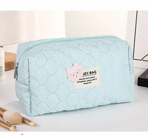 Close-up of quilted light blue makeup bag with pink bear embroidery and zipper detail