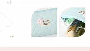 Detail of blue quilted makeup bag with pink bear patch and organized storage space