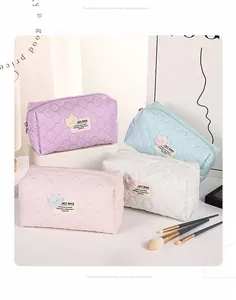 Close-up of four quilted bubble bear cosmetic bags in purple, blue, pink, and white colors