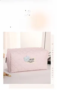 Detail of pink quilted makeup bag with cute blue bear embroidery and top zipper closure
