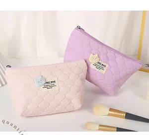 Detailed close-up of quilted cosmetic bags with cute bear patches and metal zippers