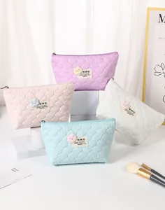 Detailed macro view of quilted makeup bags with plush bears in pastel macaron colors