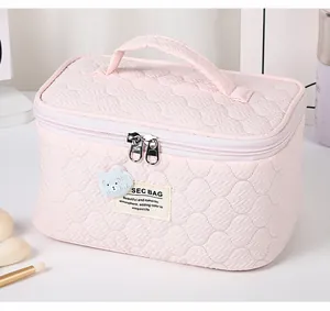 Detailed shot of pink quilted fabric makeup bag featuring bear embroidery and zipper closure