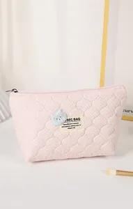 Detail of pink quilted makeup bag with bear patch and SEC BAG label