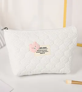 Detailed quilted heart texture of white makeup bag with pink bear embroidery