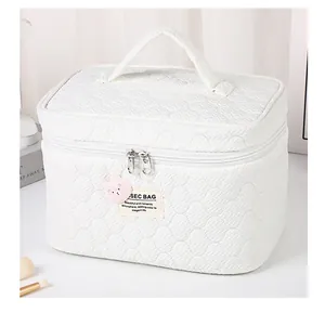 Detalle de neceser acolchado blanco con asa reforzada y colgante de oso rosa