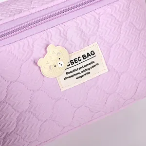 Purple quilted makeup bag with 3D texture and cute yellow bear patch detail
