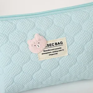 Quilted light blue cosmetic bag with cute pink bear patch and top zipper closure