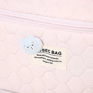 Neceser acolchado rosa con parche de oso azul y detalle de etiqueta de texto