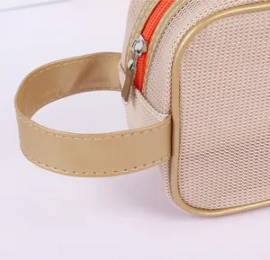 Detalle del neceser de malla champán con cremallera naranja y asa de cuero sintético dorado