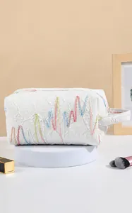 Detail van witte make-uptas met reliëftexturen en een handige dubbele ritssluiting