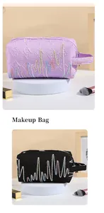 Dettaglio di trousse per il trucco viola e nere con ricami a onde e tessuto operato