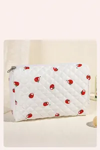 Detailopname van de gewatteerde make-uptas met tomatenprint en zilveren ritssluiting