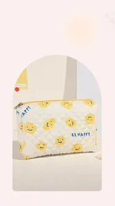 Nahaufnahme der cremefarbenen gesteppten Kosmetiktasche mit blauen Smileys und Text
