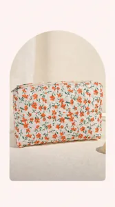 Detail van gewatteerde make-uptas met oranje bloemenprint en grote openingsontwerp