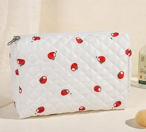 Detail van een gewatteerde toilettas met tomatenprint en zilveren metalen ritssluiting