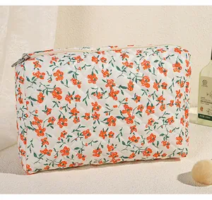 Detail van gewatteerde cosmetische tas met bloemenpatroon en metalen ritssluiting