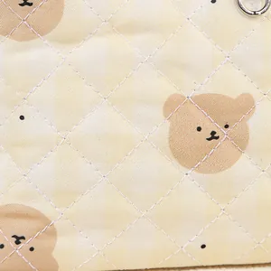 Quilted beige cosmetic bag with brown bear prints and a silver metal ring attachment