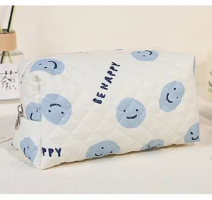 Close-up of quilted cotton makeup bag with blue smiley faces and Be Happy slogan