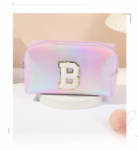 Close-up of holographic laser pink makeup bag featuring an embroidered letter B patch