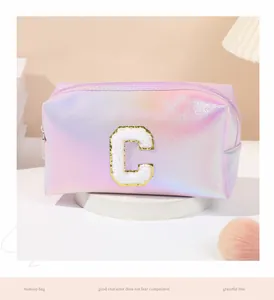 Close-up of iridescent laser makeup bag with large white towel embroidered letter C