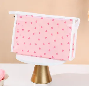 Detail shot of neat stitching and white trim on a pink heart pattern makeup bag