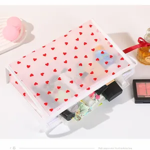 Rosa Kosmetiktasche aus Netzstoff mit roten Herzen zeigt die Aufbewahrung von Make-up