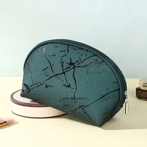 Pochette per trucco verde scuro marmorizzata con cerniera argentata su supporto circolare