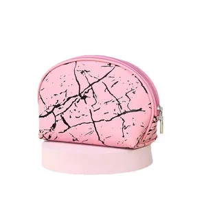 Beauty case rosa con motivo marmorizzato e cerniera su piedistallo per il viaggio