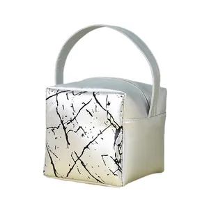 Silver metallic makeup bag with marble pattern panel and top handle in a cubic shape
