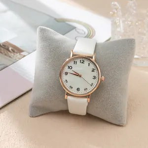 Detailed shot of white leather quartz watch with rose gold case on a velvet pillow