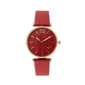 Detail of red leaf-patterned watch dial with rose gold case and woven texture strap