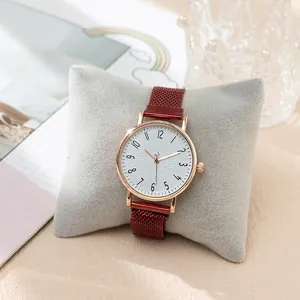 Detail of red mesh strap watch with rose gold case on a soft grey cushion display