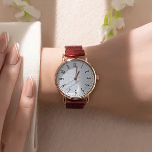 Detail of rose gold quartz watch with deep red mesh strap on model wrist