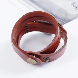 Gros plan d'un bracelet de montre enveloppant en cuir marron avec rivets et boutons bronze