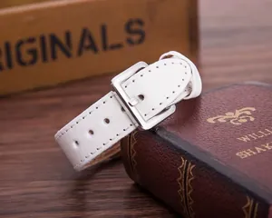 Detail of white leather watch strap with silver buckle on vintage wooden background