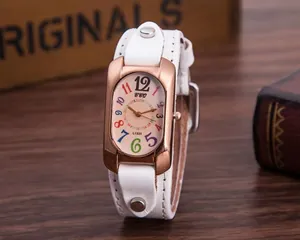 Close-up of rose gold rectangular watch with colorful digits and white studded strap
