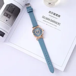 Detail of rose gold heart quartz watch with light blue woven leather strap and diamond dial